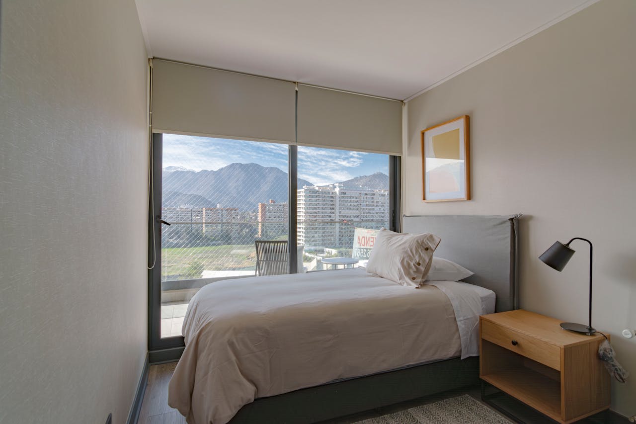 hero-img-02 Contemporary bedroom featuring a mountain view through large windows, spacious and inviting.